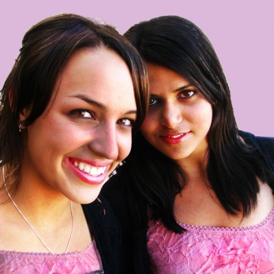 two friends in pink dresses smiling and looking at the camera