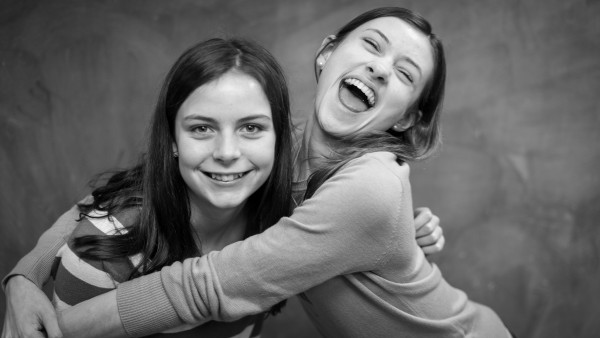 Friends List: black-and-white photo of 2 young girls laughing, smiling, and embracing each other