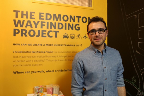 University Guiding Principles: photo of a man standing in front of an informational sign for the Edmonton Wayfinding Project