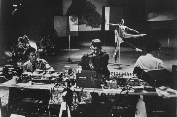 Indeterminacy: a black and white photograph of John Cage, other artists, and dancers, working on Variations 13