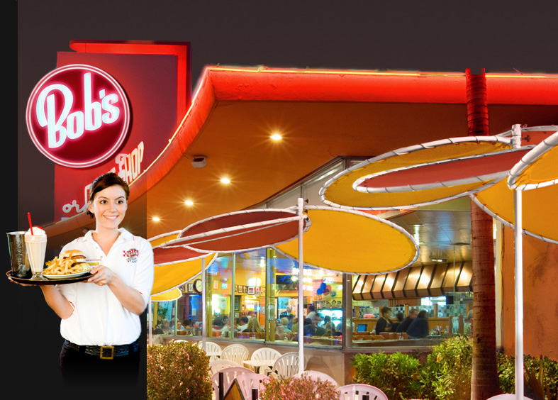 Photo of a waitress with a tray of food including burgers, fries, and drinks, standing out front of Bob's Big Boy restaurant in Burbank, California