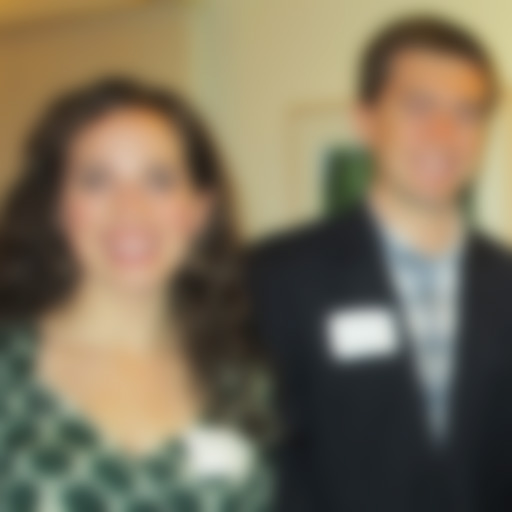 out-of-focus color photograph of a woman in a dress and a man in a suit looking at the camera