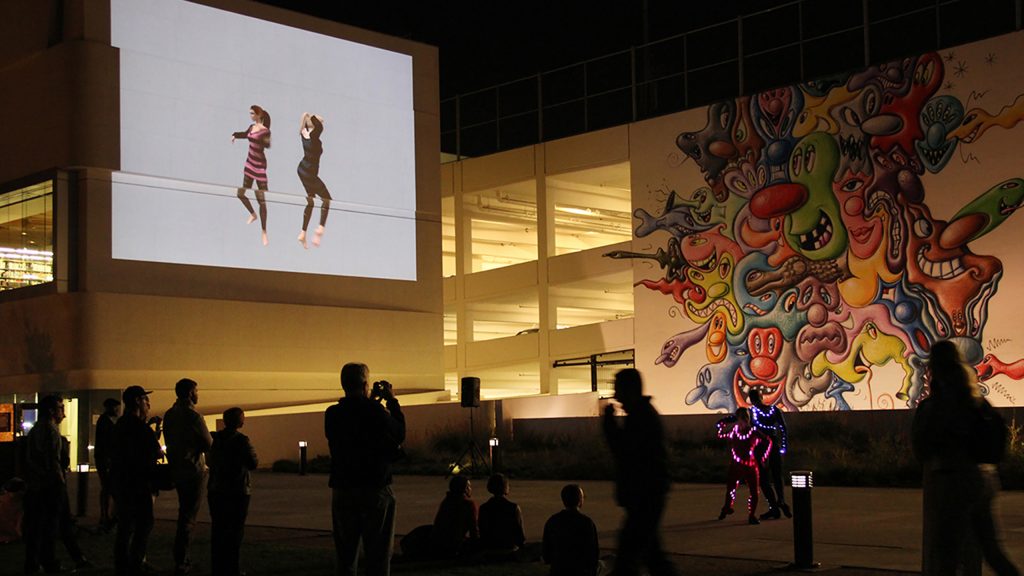 Vanessa Blaylock Company dancers projected onto a large parking structure wall as Donna Sternberg Dancers perform on the ground at ONE NIght